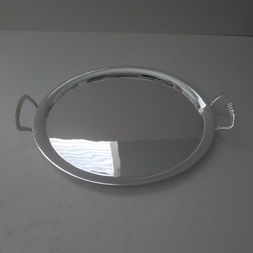 fig 2. An oval silver-plated cocktail tray featuring a flat polished surface, raised rim, and two geometric angular side handles.