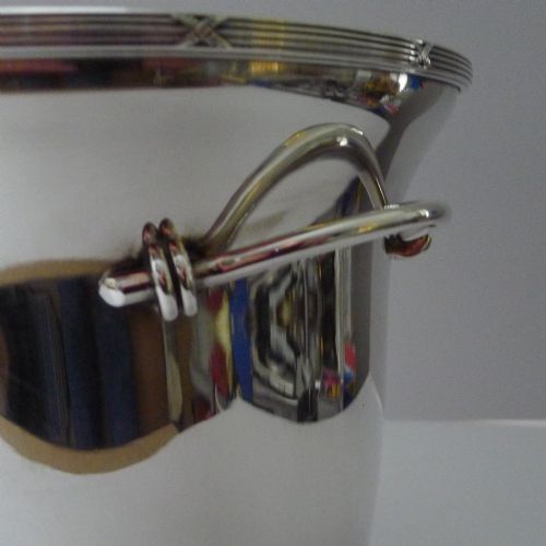 fig 1. A polished silver-plated French champagne bucket with twin side handles and a detailed reeded rim.