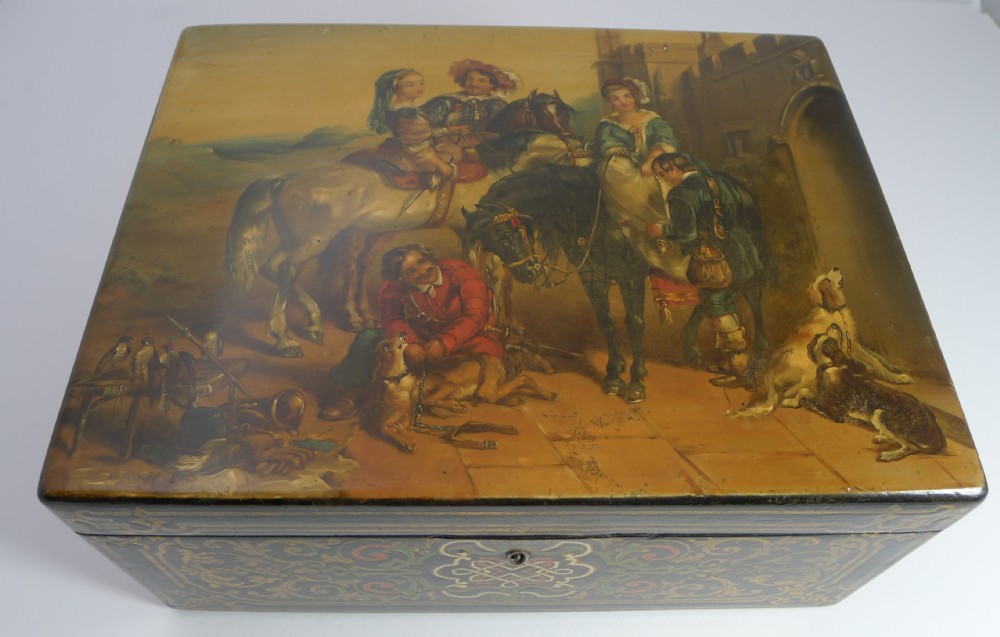 A rectangular Victorian papier-mache jewellery box depicting an equestrian hunting scene on the lid with gilt decorative scrollwork along the front.