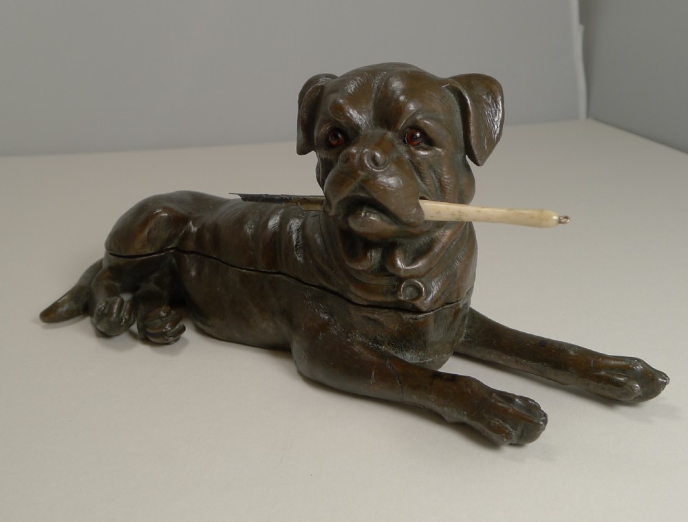 A dark brown patinated bronze inkwell sculpted in the shape of a lying Bullmastiff holding a dip pen in its mouth. View II