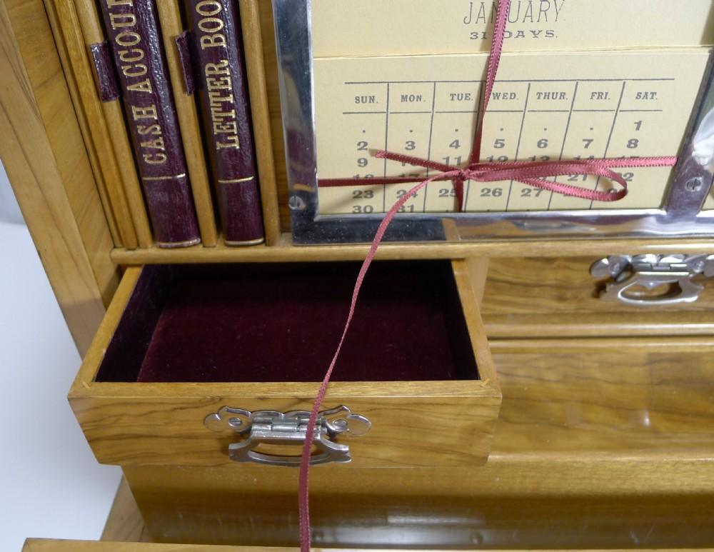 An open Victorian olivewood writing box cabinet displaying a burgundy velvet fold-out slope, internal drawers, stationery slots, and desk accessories. View VII