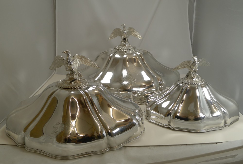 A set of three graduated silver meat domes with lobed bodies and detailed eagle finials. View II