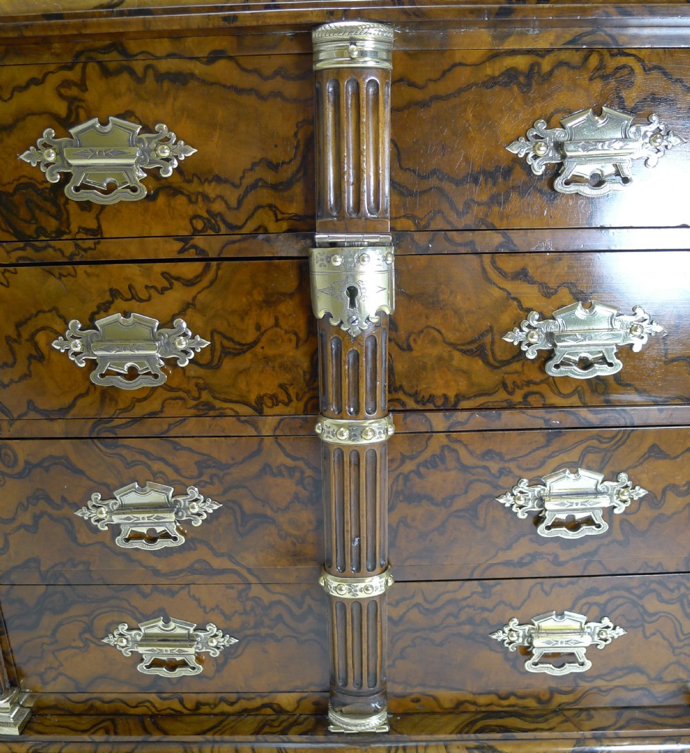 A late Victorian burr walnut cigar cabinet featuring fluted corner columns, ornate brass drawer handles, four stacked drawers, and a central locking bar with a black key tassel. View IX