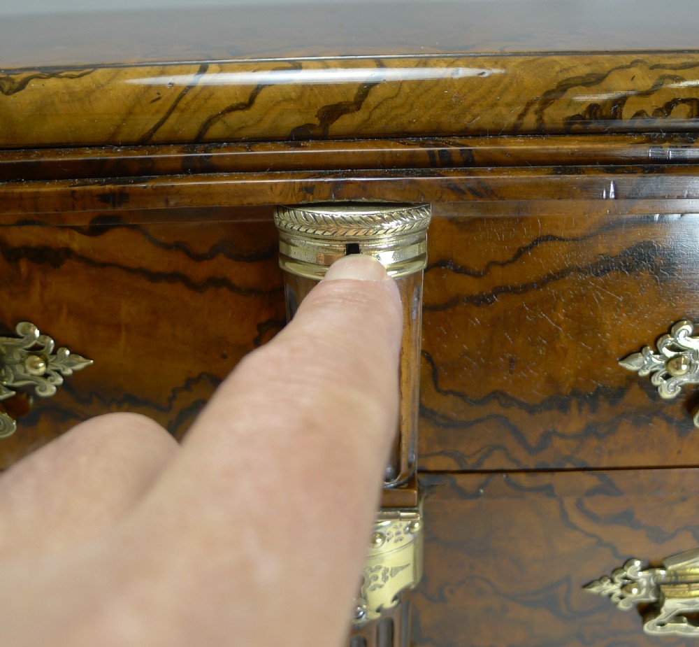 A late Victorian burr walnut cigar cabinet featuring fluted corner columns, ornate brass drawer handles, four stacked drawers, and a central locking bar with a black key tassel. View X