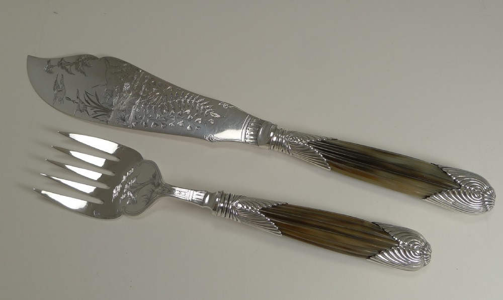 A cased pair of late Victorian fish servers featuring engraved silver-plated blades with hunting dog motifs and fluted horn handles. View X
