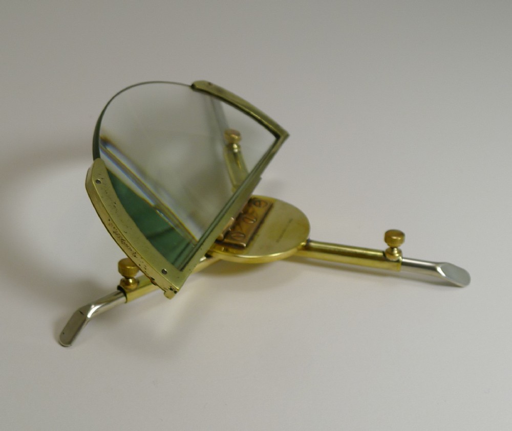 An Edwardian brass and glass folding magnifying lens featuring adjustable knurled screws and an articulated support structure.