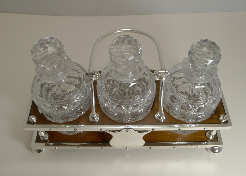 Late Victorian oak and silver-plated tantalus frame holding three cut-glass decanters with faceted stoppers. View IV