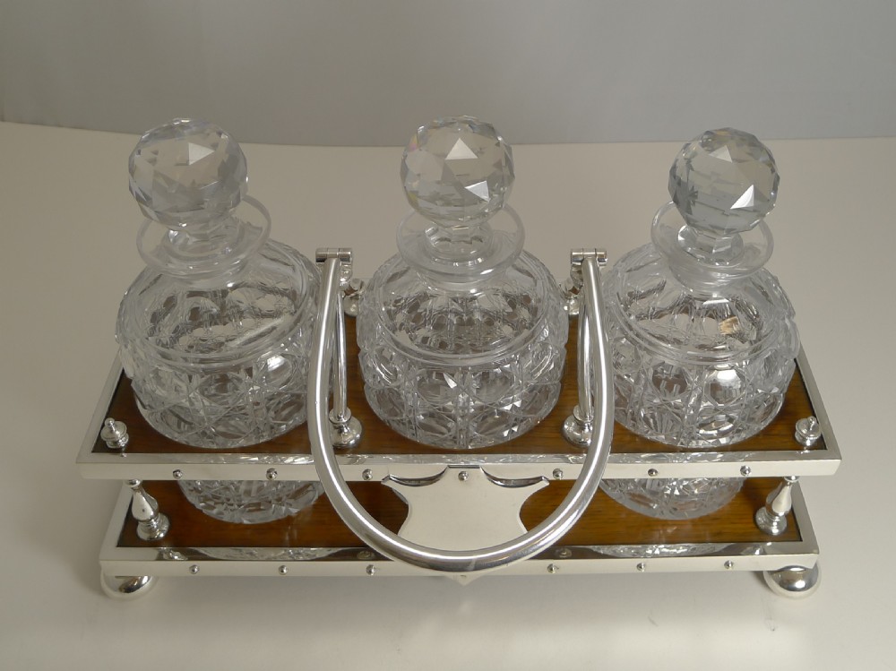 Late Victorian oak and silver-plated tantalus frame holding three cut-glass decanters with faceted stoppers. View V