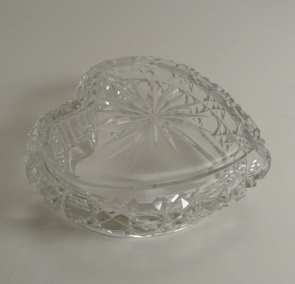 A heart-shaped cut crystal dressing table box with an embossed sterling silver lid featuring scroll foliage motifs. View V