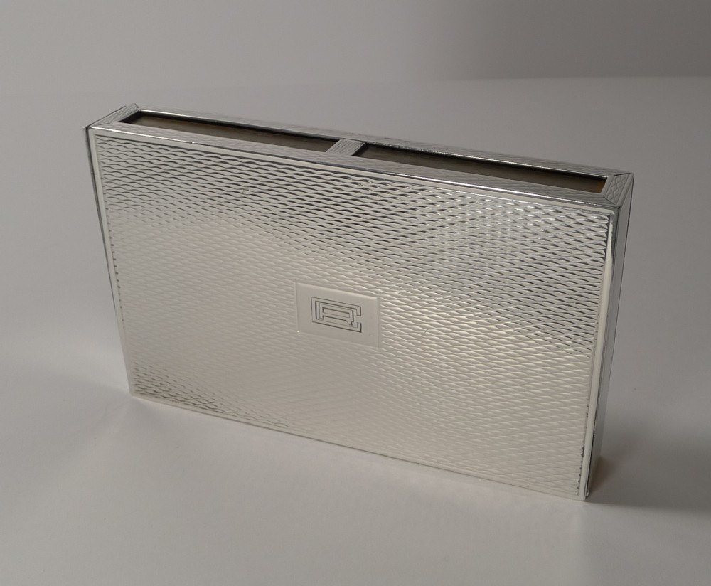 A rectangular sterling silver box with a fine engine-turned geometric pattern and a central engraved monogram.