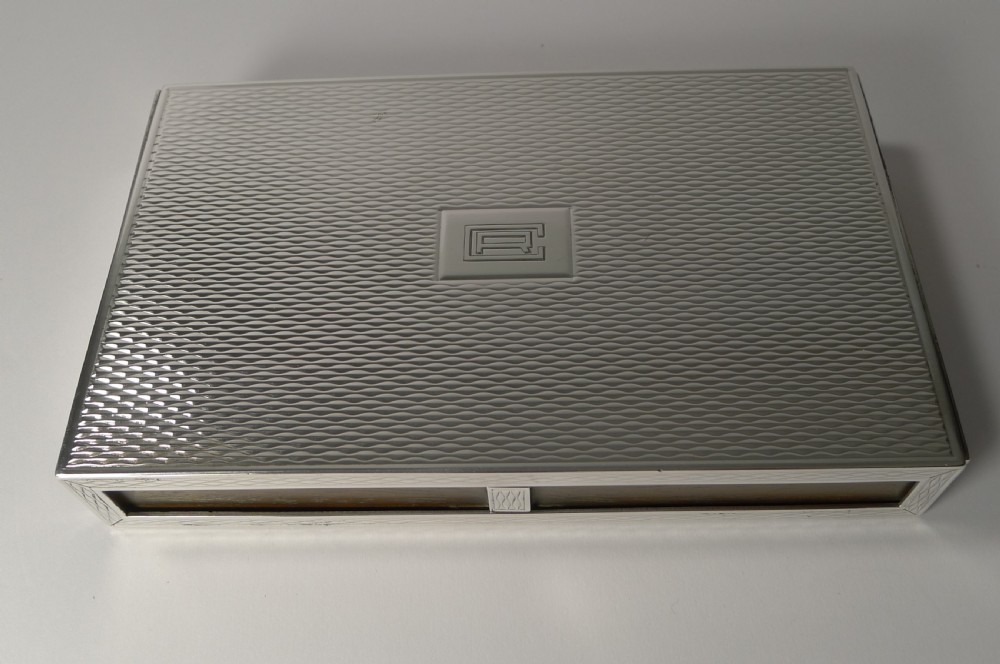 A rectangular sterling silver box with a fine engine-turned geometric pattern and a central engraved monogram. View VII