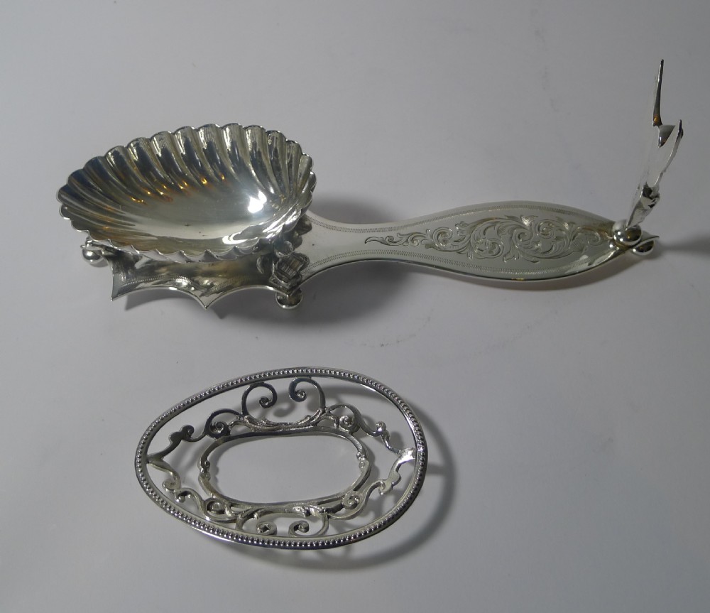 An engraved Victorian silver-plated spoon rest featuring a pierced scrollwork bowl, foliage engraving, and a cast winged cherub figure standing on ball feet. View VII