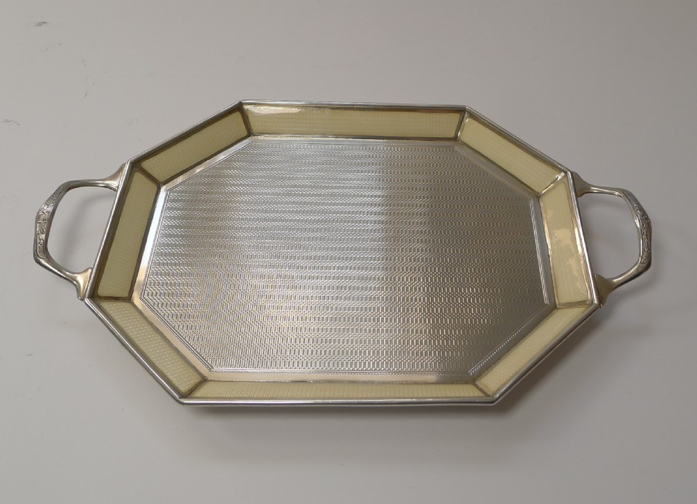 An octagonal sterling silver tray featuring a central engine-turned pattern, a cream guilloche enamel border, and integrated side handles. View IV