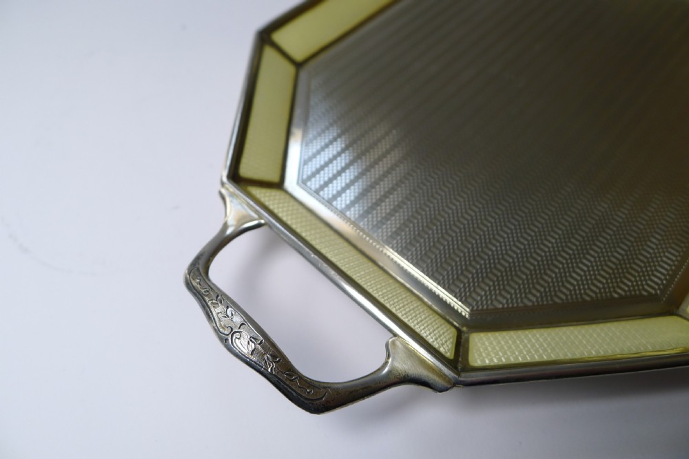 An octagonal sterling silver tray featuring a central engine-turned pattern, a cream guilloche enamel border, and integrated side handles. View VII