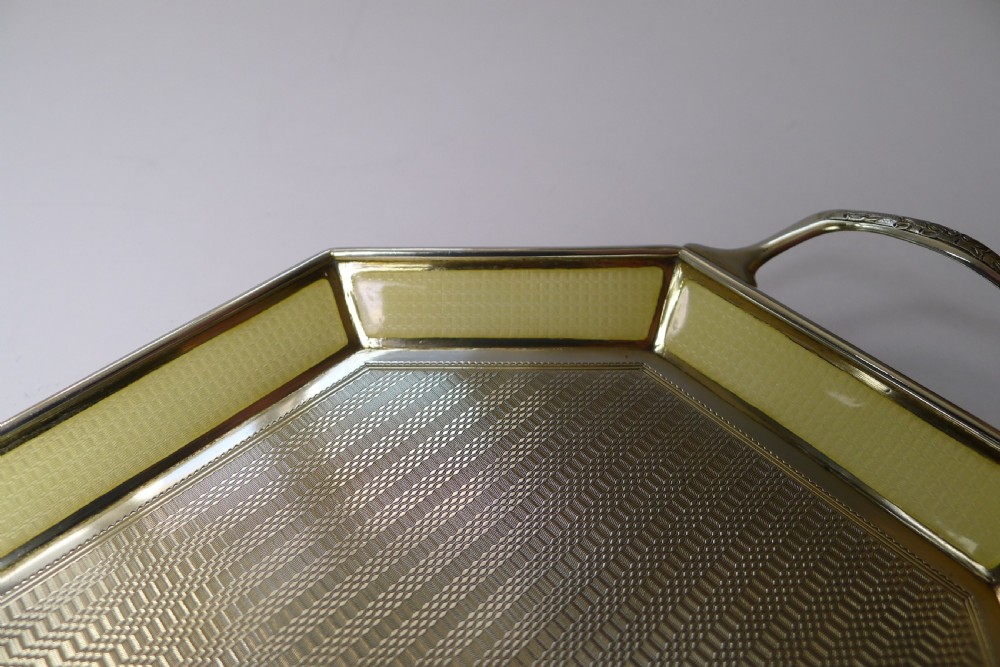 An octagonal sterling silver tray featuring a central engine-turned pattern, a cream guilloche enamel border, and integrated side handles. View IX