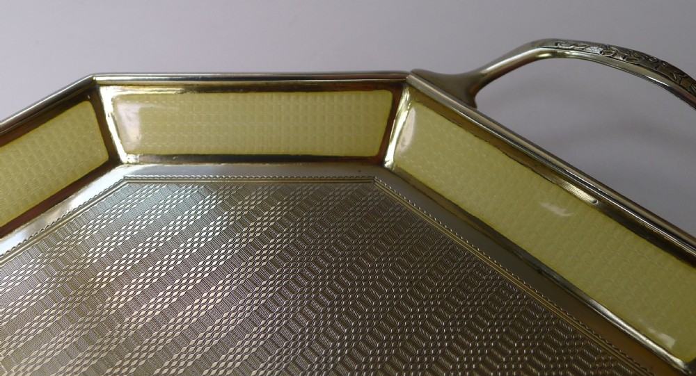 An octagonal sterling silver tray featuring a central engine-turned pattern, a cream guilloche enamel border, and integrated side handles. View X