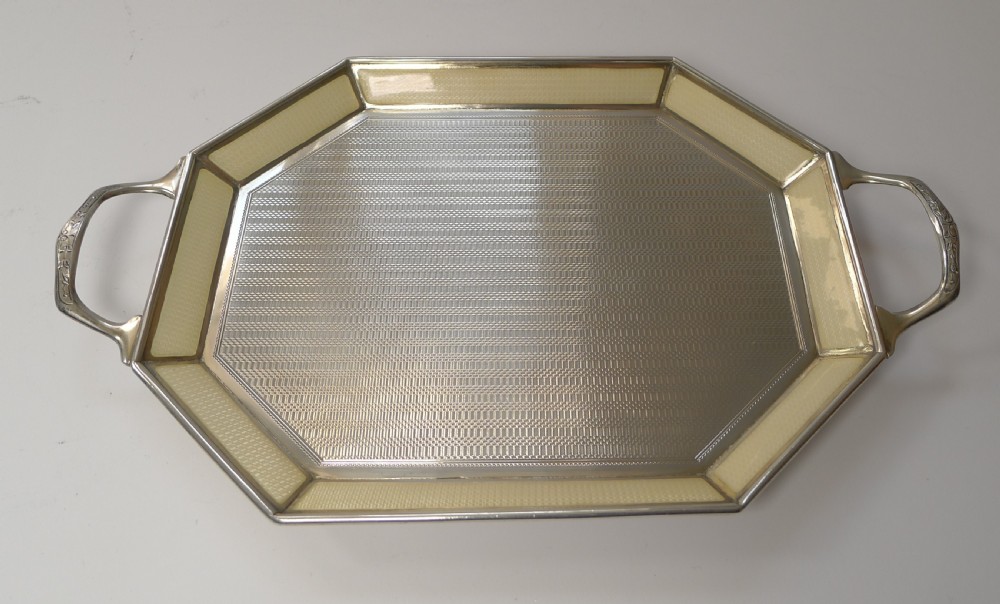 An octagonal sterling silver tray featuring a central engine-turned pattern, a cream guilloche enamel border, and integrated side handles. View XII