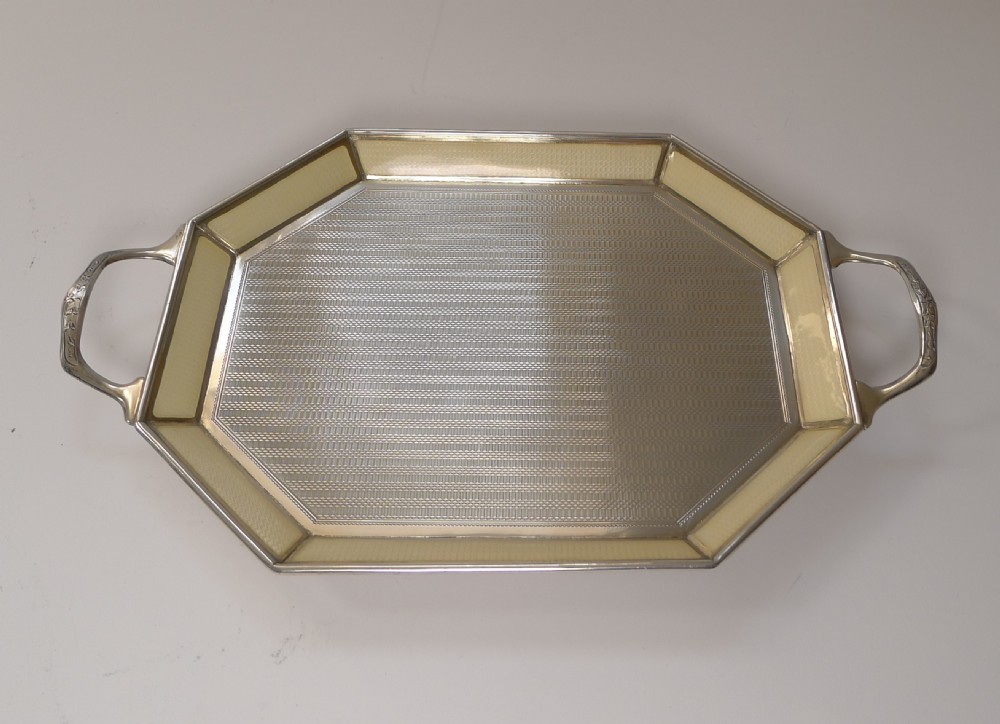 An octagonal sterling silver tray featuring a central engine-turned pattern, a cream guilloche enamel border, and integrated side handles. View XVII
