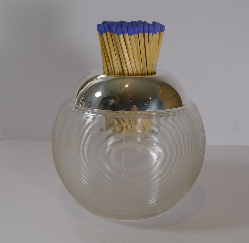 A spherical ribbed clear glass match strike featuring a polished sterling silver rim collar containing wood matches.