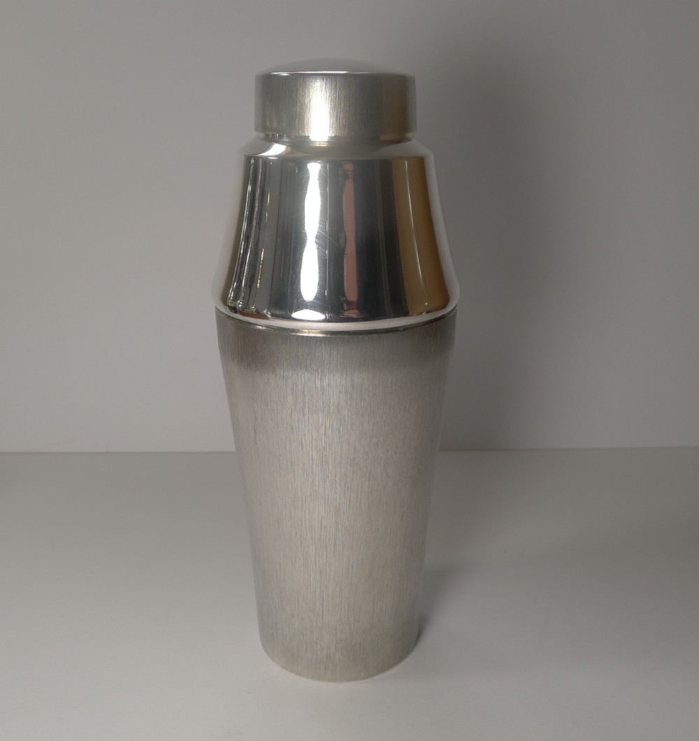 A three-piece mid-century silver-plated cocktail shaker featuring a brushed metal lower body, a polished tapered upper section, and a smooth top cap.