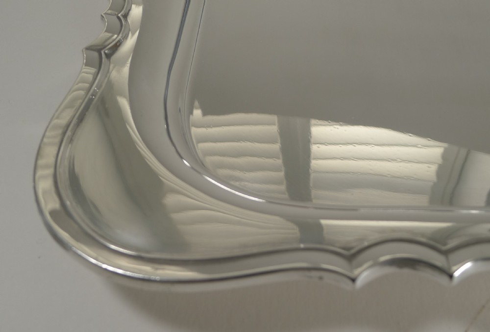A rectangular silver-plated serving tray featuring moulded scalloped edges, integrated side handles, and a polished reflective surface. View IV