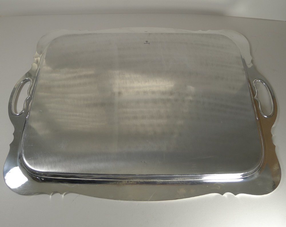 A rectangular silver-plated serving tray featuring moulded scalloped edges, integrated side handles, and a polished reflective surface. View VII