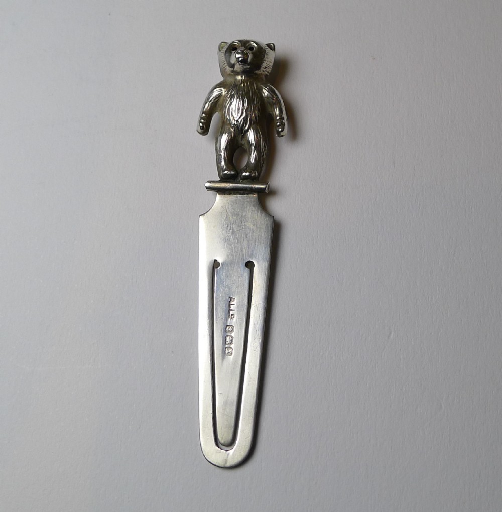 An antique sterling silver bookmark featuring a cast three-dimensional teddy bear finial at the top and British hallmarks stamped along the flat clip blade.
