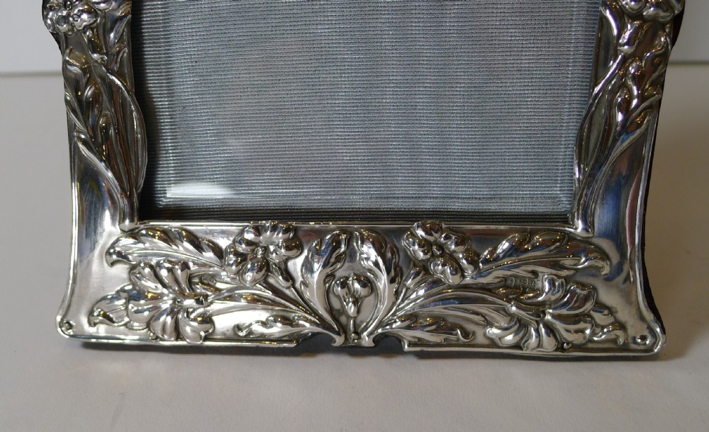 An Edwardian sterling silver Art Nouveau photograph frame featuring relief floral motifs and organic scrolling borders. View II
