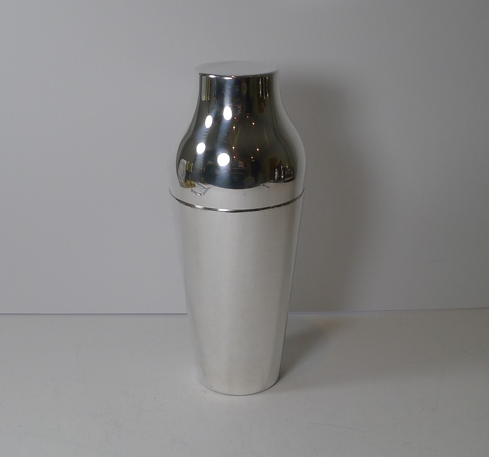 A two-piece modernist silver-plated cocktail shaker featuring a tapered lower body and a polished contoured cap.