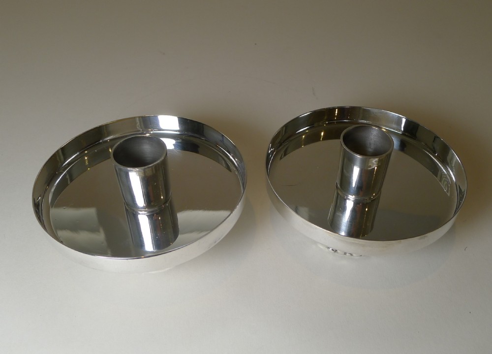A pair of silver-plated modernist candlesticks featuring wide shallow circular drip trays, cylindrical sockets, and pebbled textured bases. View XIII