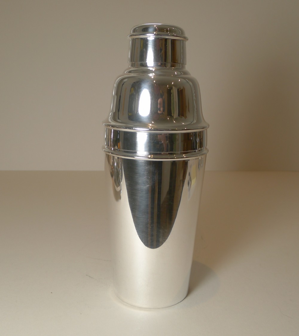 A polished silver-plated three-piece Art Deco cocktail shaker featuring stepped rims and a tapered body.