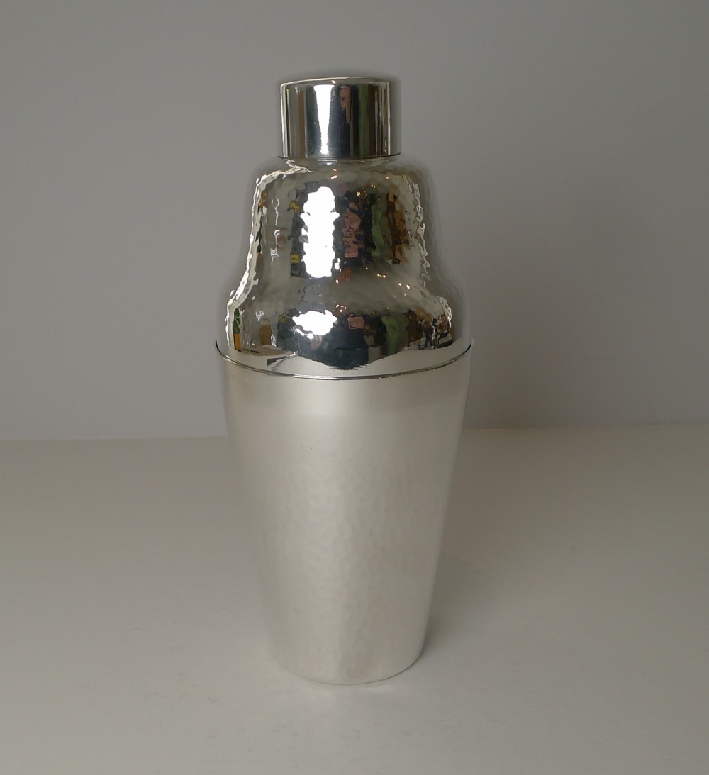 An Art Deco silver-plated three-piece cocktail shaker featuring a hammered texture upper body and a smooth tapered base.