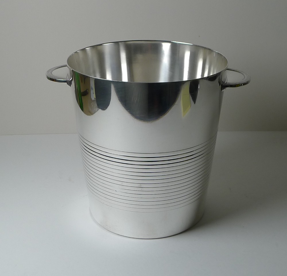 A silver-plated Art Deco champagne bucket featuring parallel horizontal reeded lines around the body and twin curved handles.