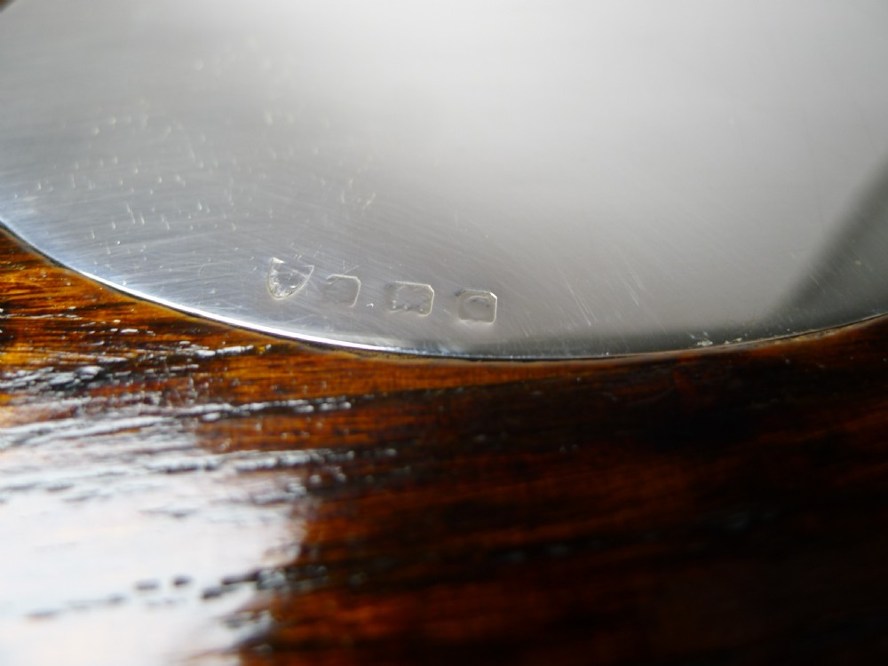 An Edwardian oval dark oak tray featuring a silver pierced gallery border, twin side handles, small bun feet, and a central oval silver medallion. View IV