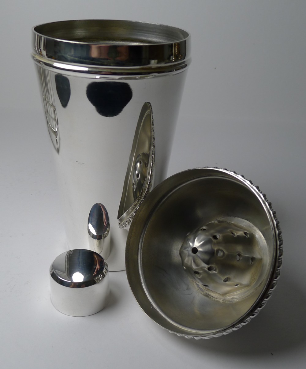 A silver-plated three-piece cocktail shaker with a high-shine polished finish and an integrated citrus reamer built into the lid assembly.