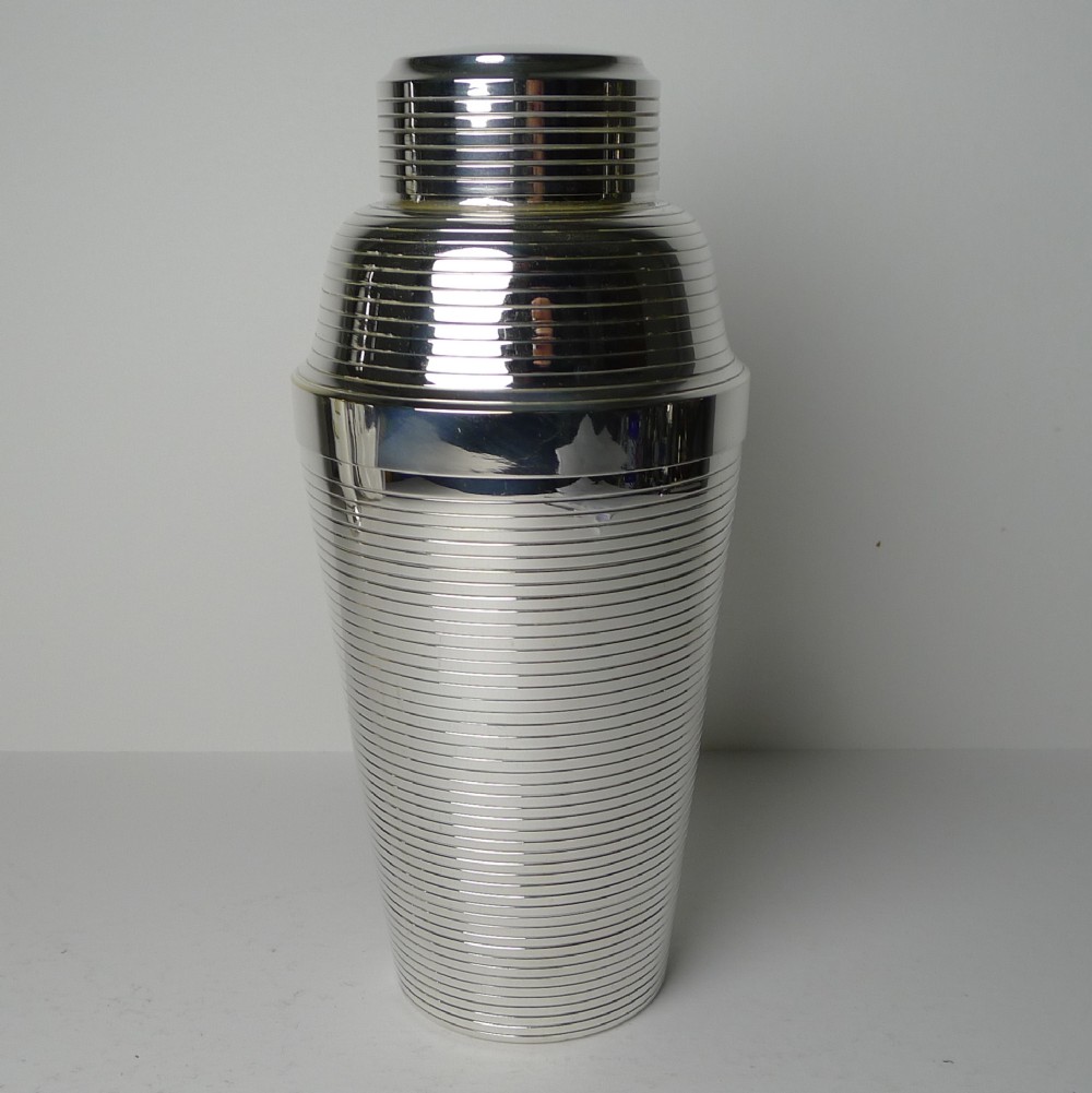 A silver-plated Art Deco cocktail shaker featuring horizontal ribbed engine-turned detailing across its cylindrical body and stepped cap.