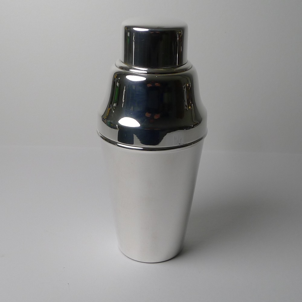 A polished silver-plated Art Deco three-piece cocktail shaker featuring a tapered lower body and a stepped cap.