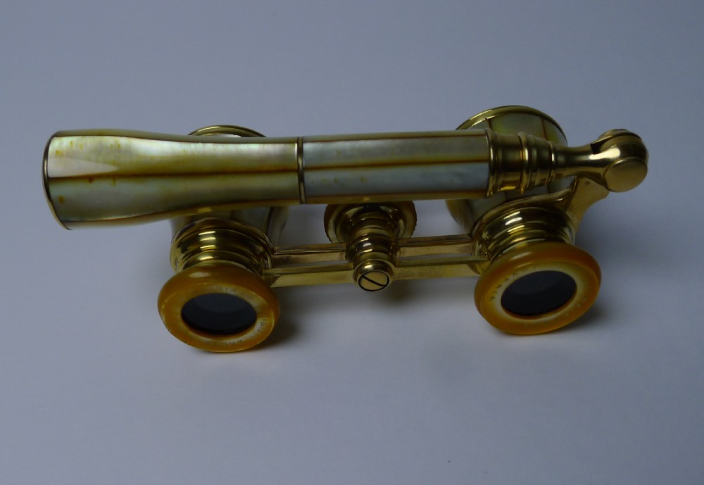 A pair of brass French opera glasses featuring iridescent mother of pearl panels and an extendable side handle. View X
