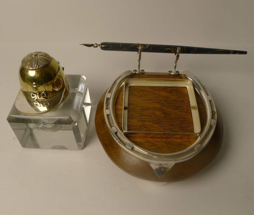A Victorian equestrian desk inkstand featuring a square glass inkwell topped with a brass jockey cap lid, mounted on a wooden base with a horseshoe motif and pen rest. View II