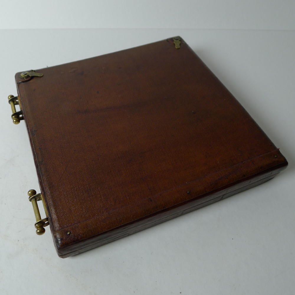 A double folding picture frame bound in brown crocodile-embossed leather featuring circular brass inner apertures and brass hinges. View III