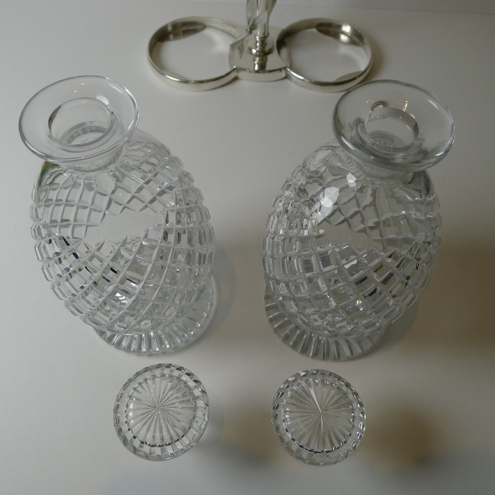 An Edwardian silver-plated double tantalus featuring a central looping frame holding two diamond-pattern cut-glass decanters. View IX