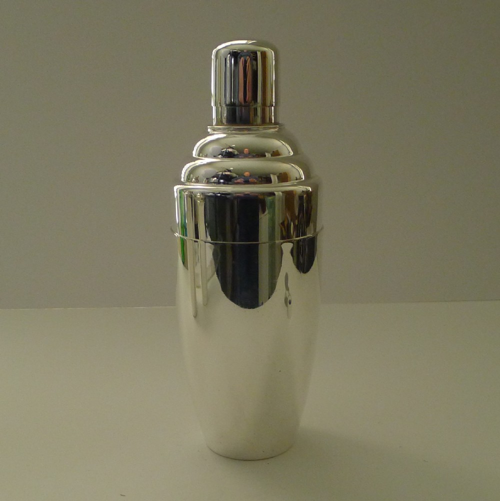 A silver-plated Art Deco cocktail shaker featuring a tapered body, stepped shoulder detailing, and a smooth domed top cap.