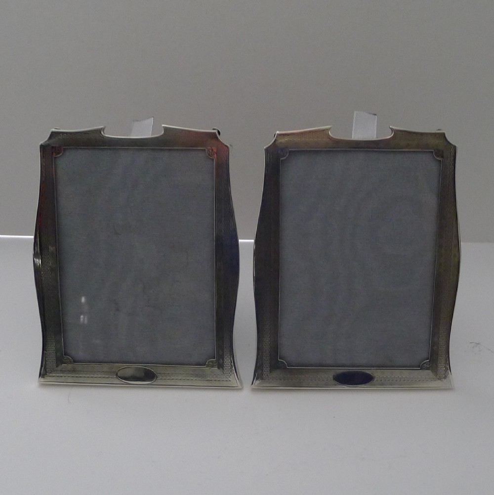 A pair of matching Art Deco silver picture frames with engine-turned geometric engraving and easel backs.