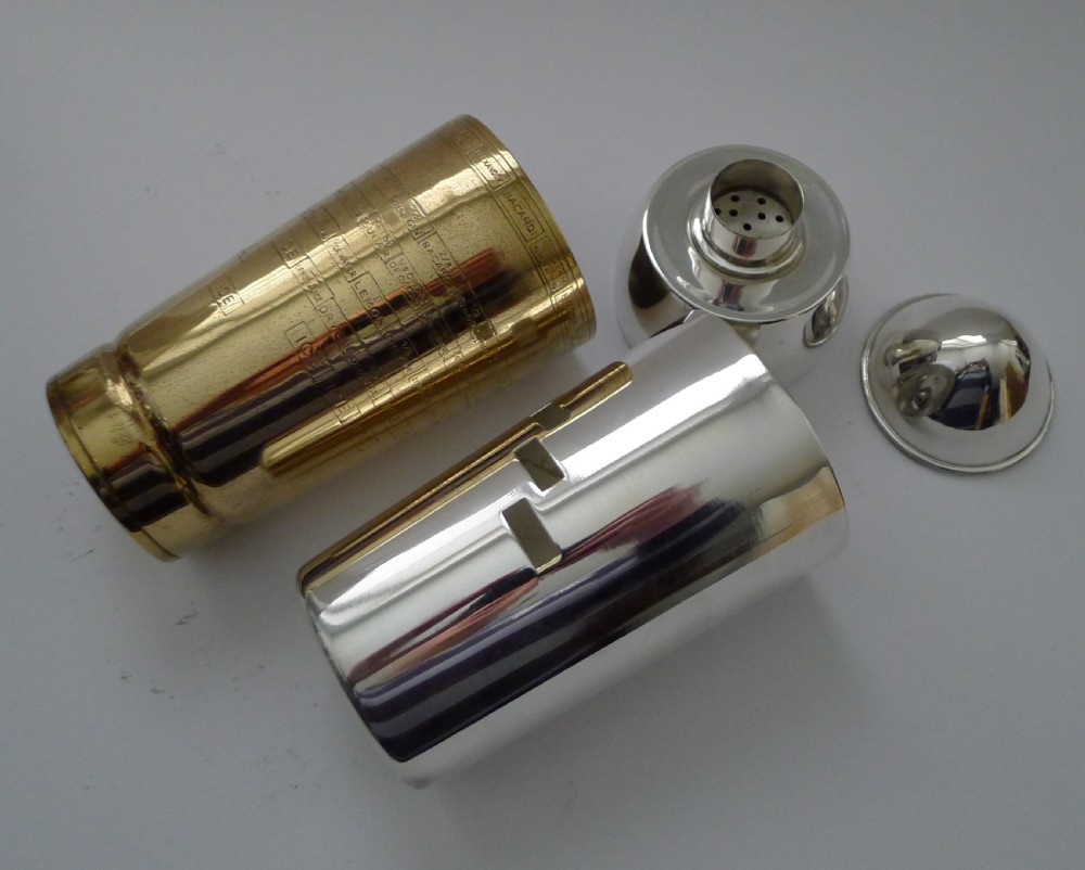 A bullet-shaped silver-plated cocktail shaker featuring a rotating brass band and cut-out windows displaying recipe ingredients. View XII