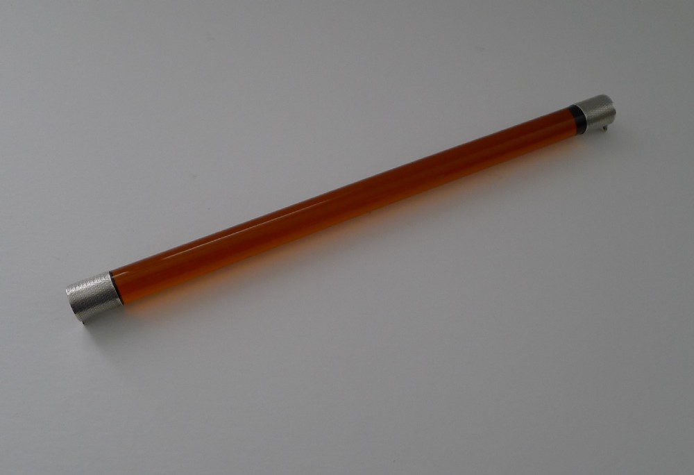 A cylindrical amber glass ruler with textured sterling silver caps fitted to each end. View IV