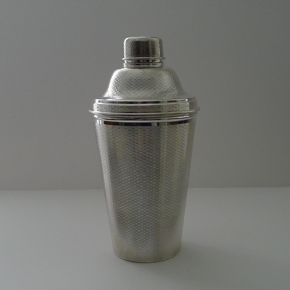 A large three-piece silver-plated Art Deco cocktail shaker featuring an engine-turned geometric pattern across the exterior.