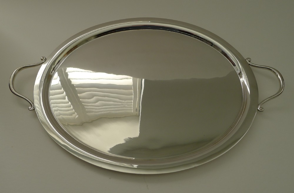 An oval silver-plated Art Deco tray featuring a polished surface, a flat raised rim, and two curved side handles. View III