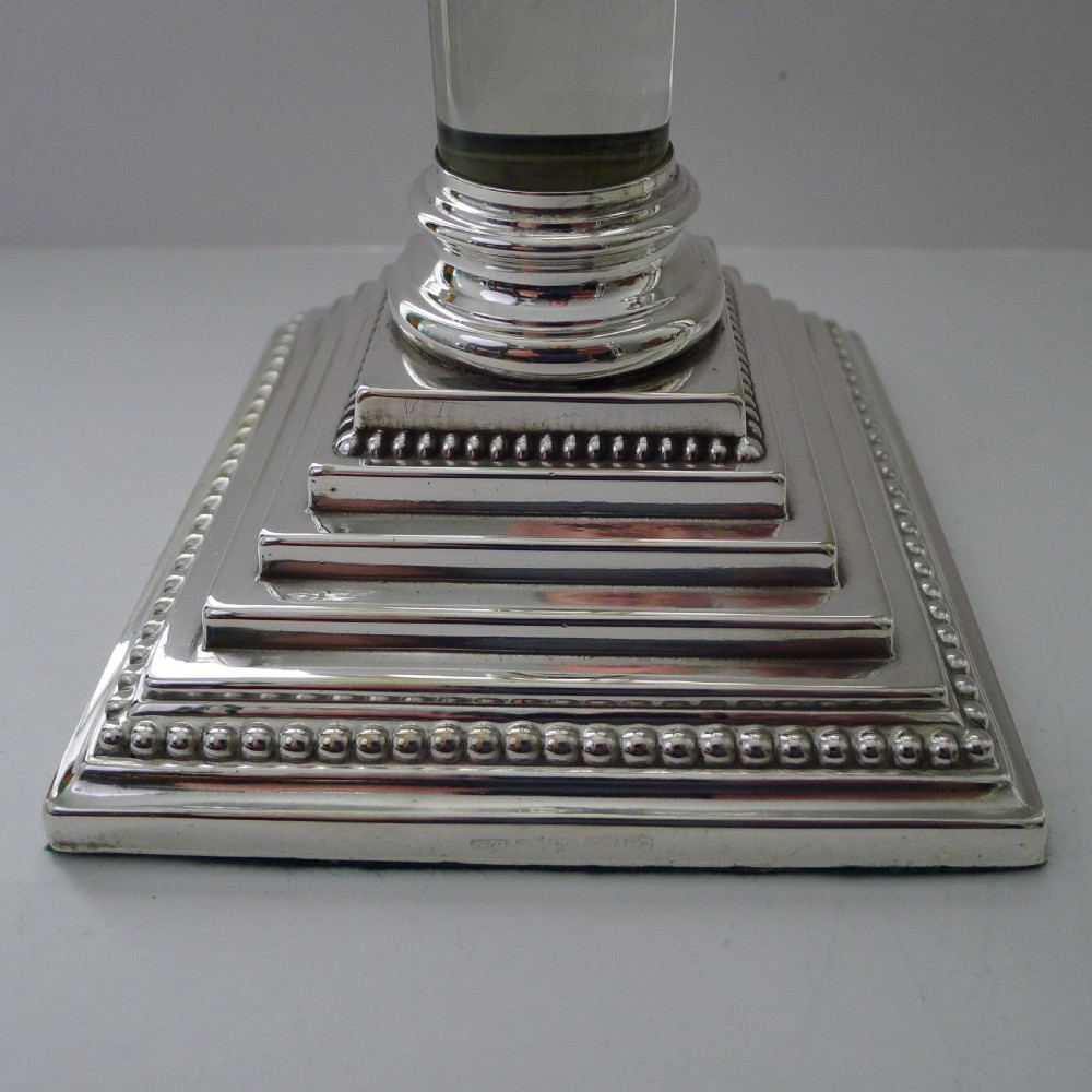 A set of four Victorian silver-plated candlesticks featuring clear glass column shafts, cast Corinthian capitals, and square stepped bases. View IV
