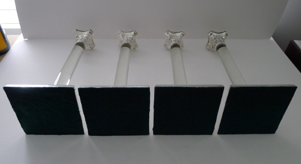 A set of four Victorian silver-plated candlesticks featuring clear glass column shafts, cast Corinthian capitals, and square stepped bases. View VI