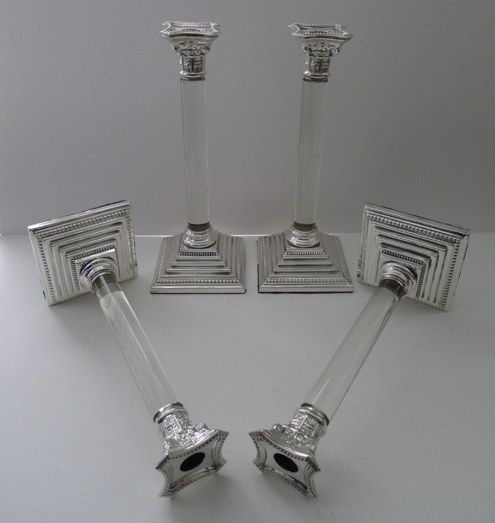 A set of four Victorian silver-plated candlesticks featuring clear glass column shafts, cast Corinthian capitals, and square stepped bases. View VII